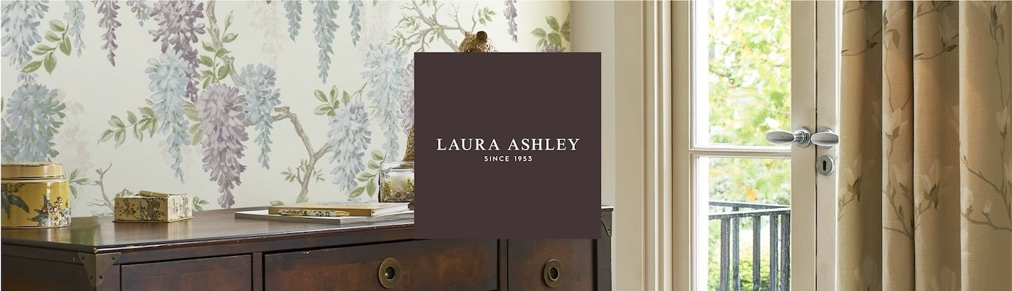 Laura Ashley Brand and logo centered over the Wisteria Pale Iris Wallpaper decorating a living oom.